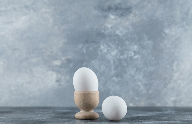 Egg cup and eggs on grey table.
