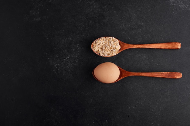 Uovo e farina in cucchiai di legno in parallelo.