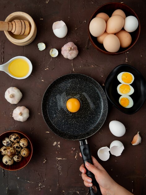 egg, garlic with butter and egg yolk in frying pan on maroon table