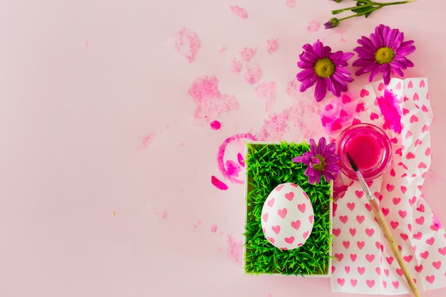 Free photo egg on grass near paint and flowers