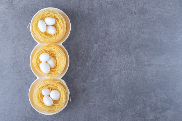 Nidi di pasta all'uovo con caramelle bianche in ciotole.