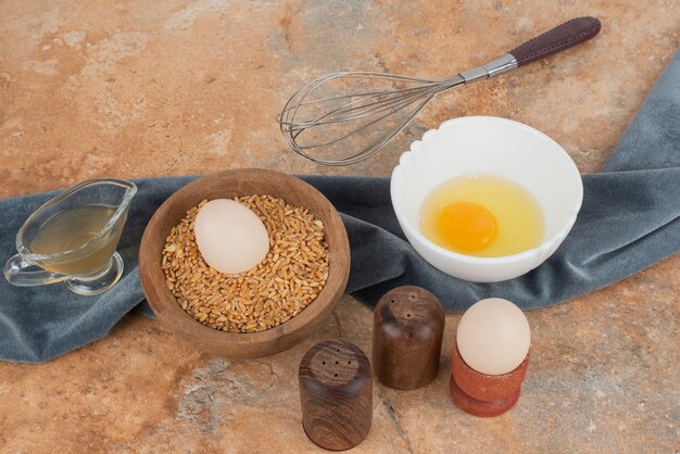 Egg and raw egg on plate on marble surface .