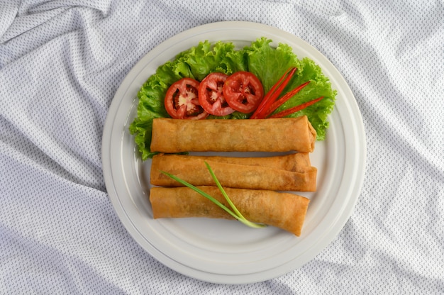Бесплатное фото Яичный рулетик или жареные блинчики с начинкой на белой плите тайской еды. вид сверху.