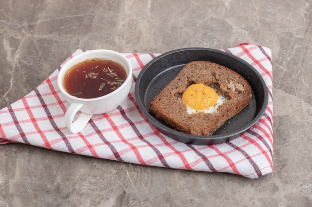 Яичный тостовый хлеб и чашка чая на скатерти. Фото высокого качества