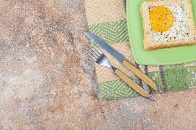 칼 붙이 및 식탁보와 녹색 접시에 향신료와 달걀 토스트