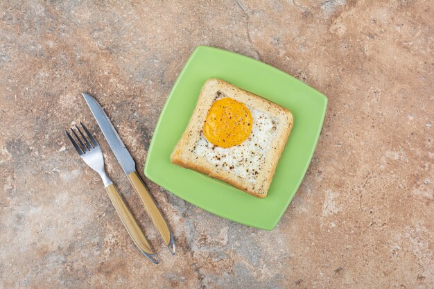 Egg toast with spices on green plate with cutlery