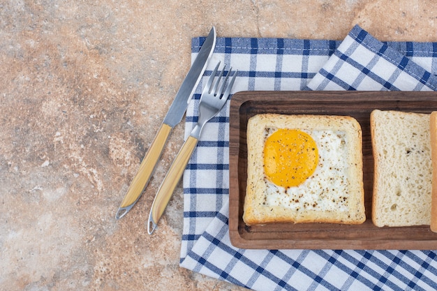 Egg toast with spices on wooden plate with cutlery