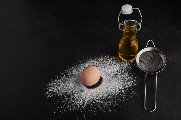 Egg with a bottle of olive oil on black space. 