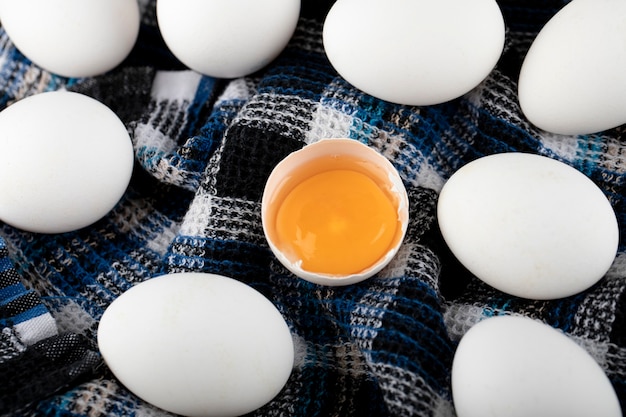 Яичный желток и белые яйца на полосатой ткани.