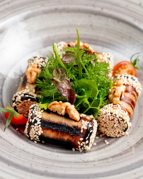Eggplant rolls served with greens tomatoes walnuts and sesame seeds