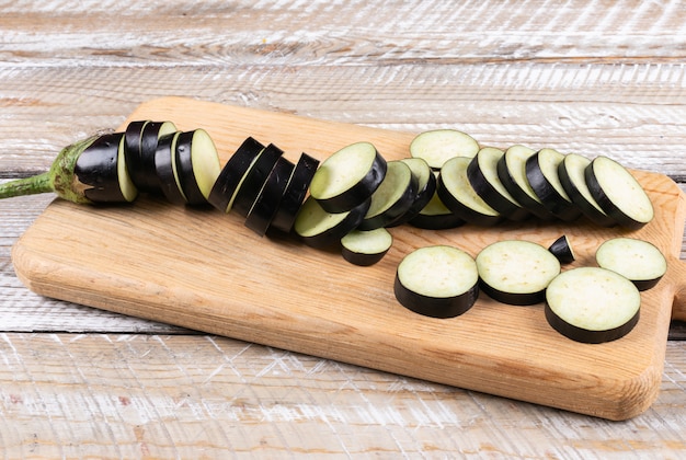 Eggplant slices in a cutting board high angle view on a wooden 