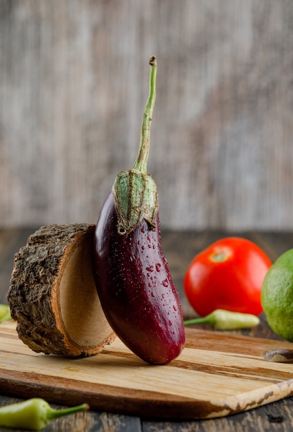 Eggplant with lemon, tomato, peppers, wood side view on wooden and cutting board