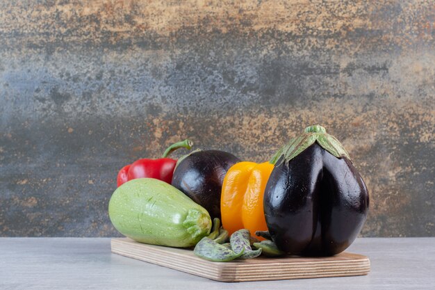 Eggplants, bell peppers and zucchini on wooden plate. High quality photo