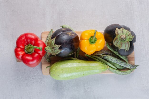 Eggplants, bell peppers and zucchini on wooden plate. High quality photo