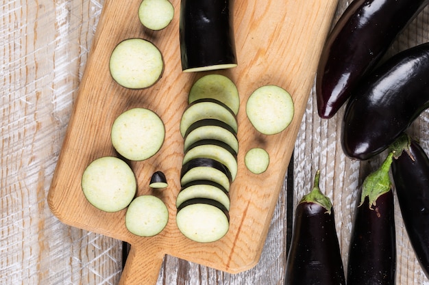 Eggplants and chopped one on a cutting board and wooden 