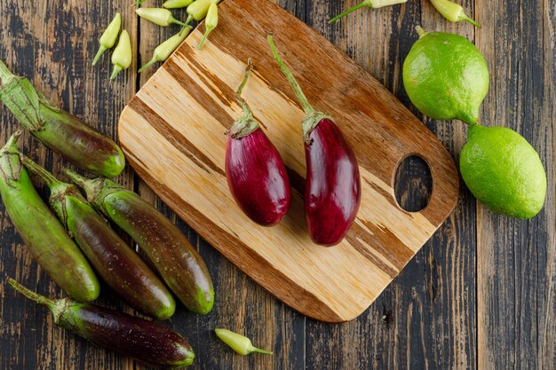 Eggplants with lemons, peppers flat lay on wooden and cutting board