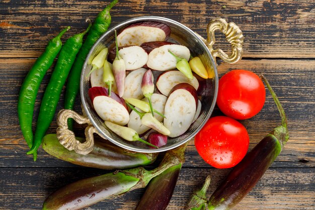 Eggplants with tomatoes, peppers in a pan on wooden, flat lay.