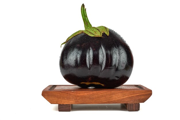 Eggplants on a wooden board on white.