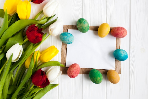 Foto gratuita uova intorno a carta vicino a tulipani