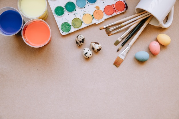 Eggs and brushes with paints on table