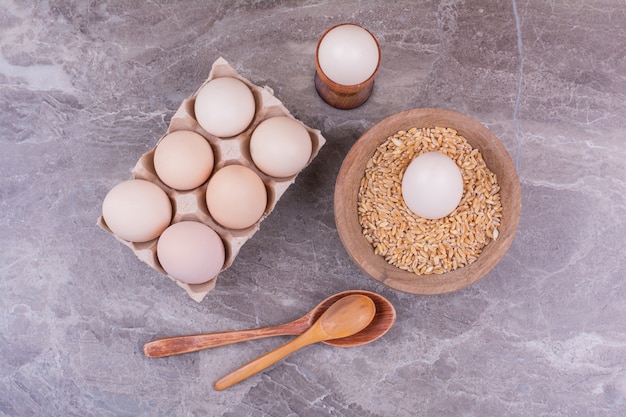 Eggs in a cardboard tray and in a wooden cup