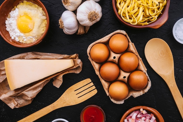 Eggs and cheese amidst pasta ingredients and utensils