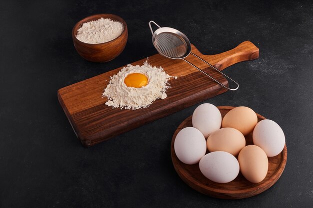 Eggs and flour as cooking ingredients on wooden board. 