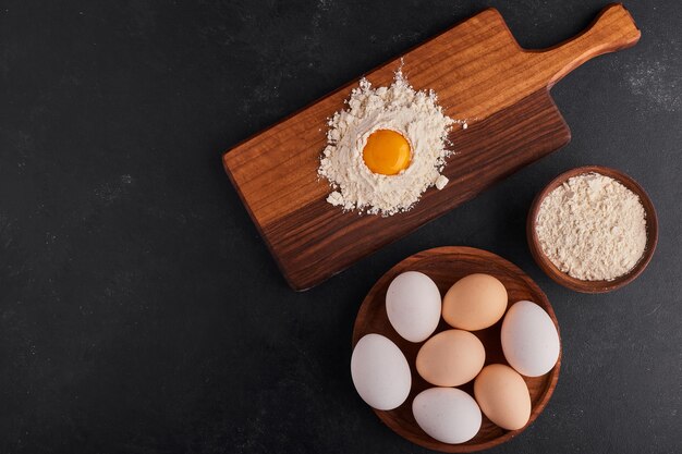 Eggs and flour in wooden platters for bakery making. 