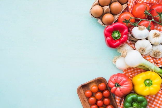 Eggs and healthy vegetables on blue colored background