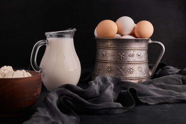 Eggs in a metallic pot with a jar of milk aside. 