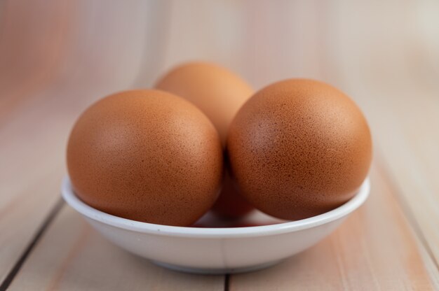 Eggs placed in a cup on a wooden floor.