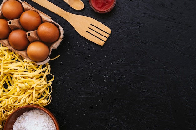 Eggs and spatula near pasta and flour