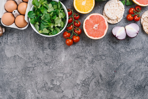 Eggs; vegetables; citrus fruit and puffed rice cake on concrete background