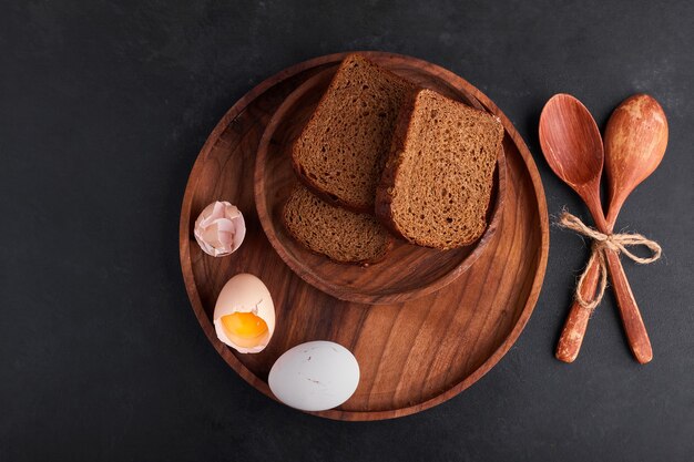 Eggs with bread slices in a wooden platter, top view. 