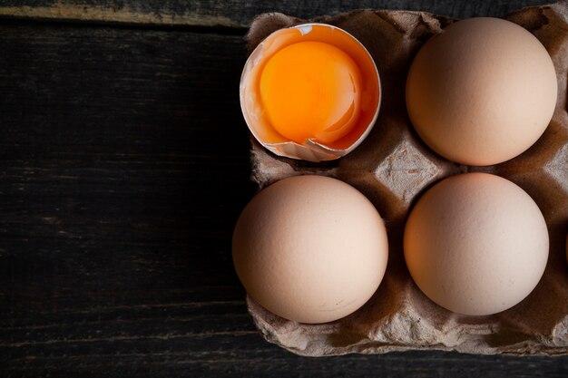 Eggs with broken one top view on a dark wooden background space for text