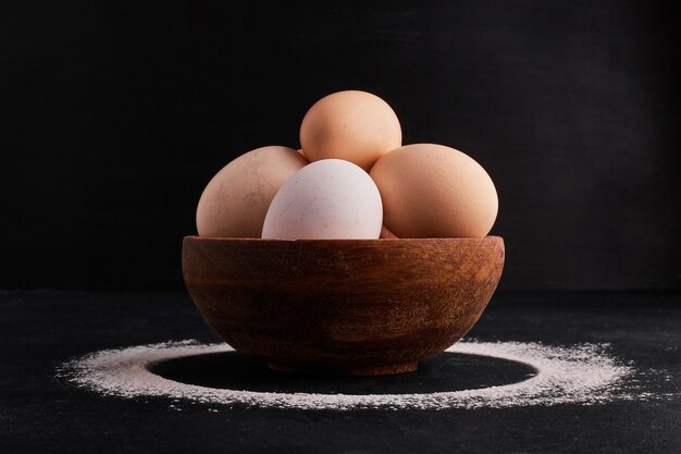 Eggs in a wooden cup on black space. 