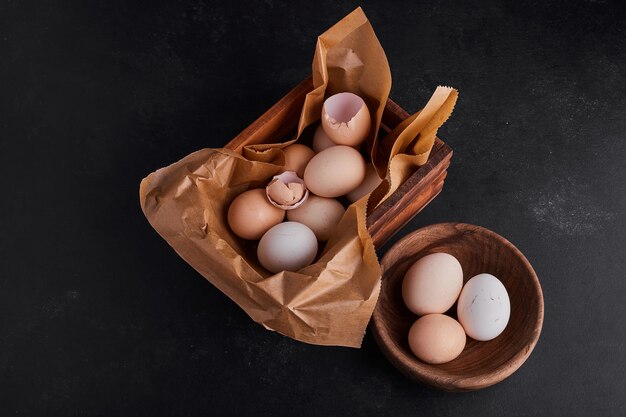 Eggs in a wooden cup and on the rustic paper. 