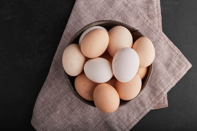 キッチンタオルの上の木製の大皿に卵、上面図。