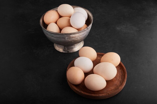 Eggs in a wooden platter and in a metallic cup. 
