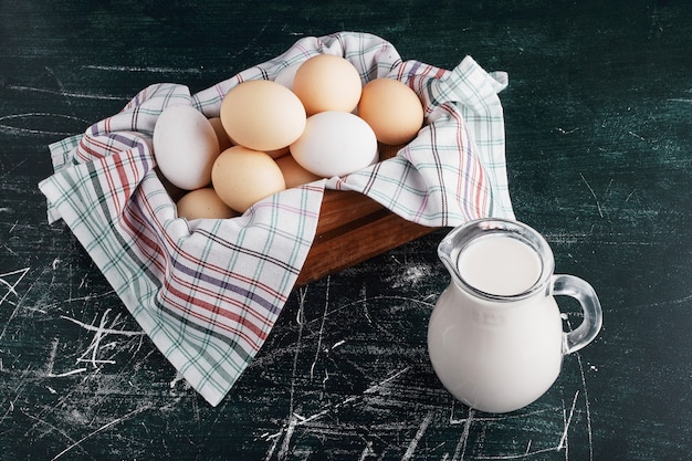 Eggs in a wooden tray with a jar of milk around.