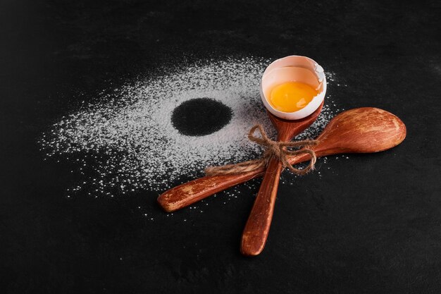 Eggshell in a wooden spoon on flour space. 