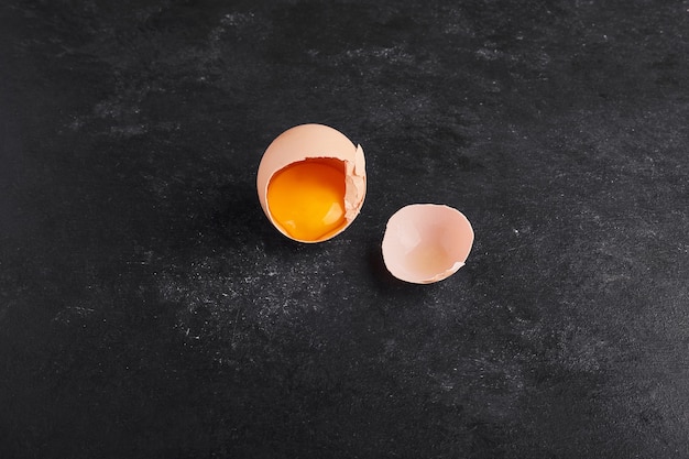 Eggshells isolated on black surface, top view. 