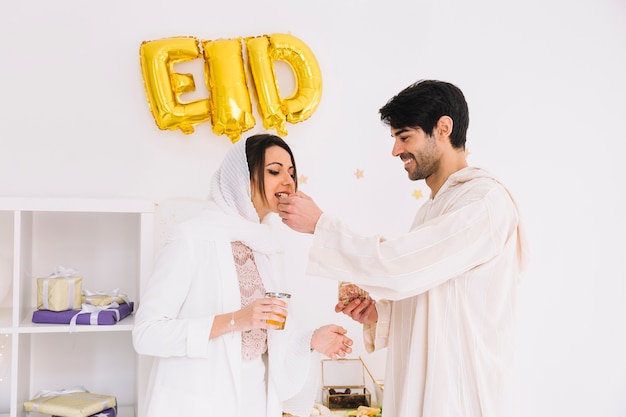 Concetto di eid al-fitr con coppia che mangia i biscotti