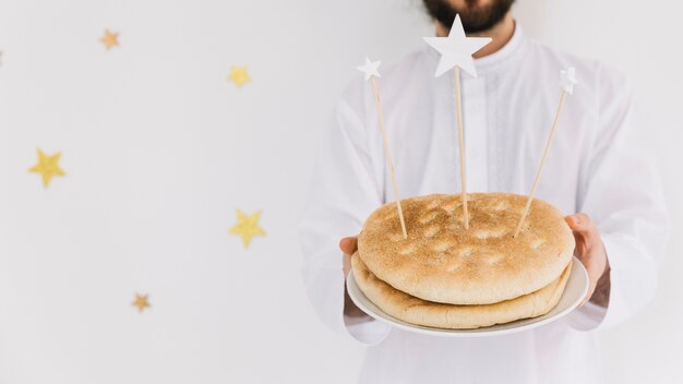 Eid al-fitr concept with man holding plate of bread