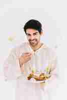 Free photo eid al-fitr concept with man presenting arab pastry