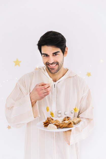 Eid al-fitr concept with man presenting arab pastry