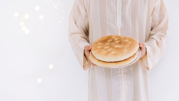 Eid al-fitr concept with muslim man holding bread