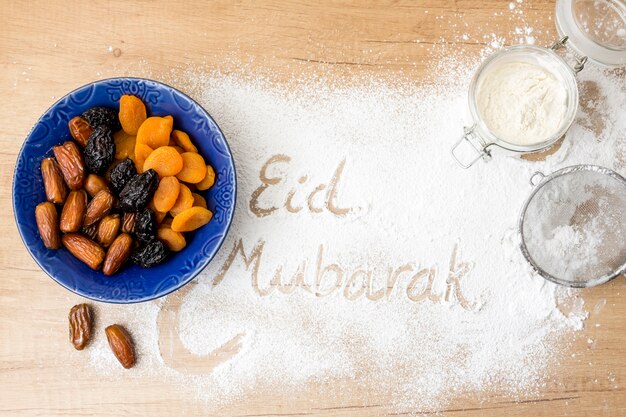Eid Mubarak inscription on flour near dried fruits 