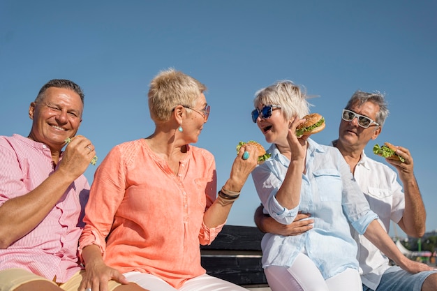 Free photo elder couples at the beach eating burgers