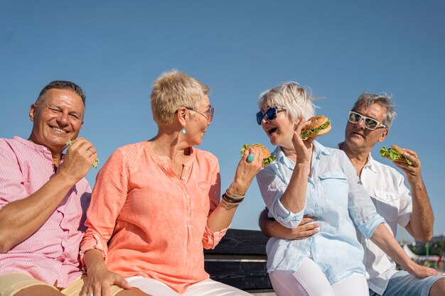 Elder couples at the beach eating burgers